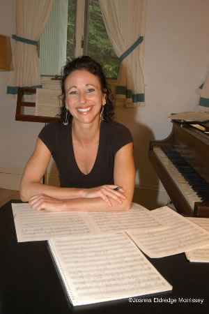 Award-winning American composer of music for opera, orchestra, chorus, chamber ensembles, dance, and multimedia collaborations Andrea Clearfield sits at a table with sheet music all over it.