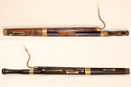 These early 1800s Bassoons were made in England. The top instrument is long and has brass bands and six brass keys. The bottom instrument is an Octave (or short) Bassoon, few of which exist and nearly all are in museum collections.