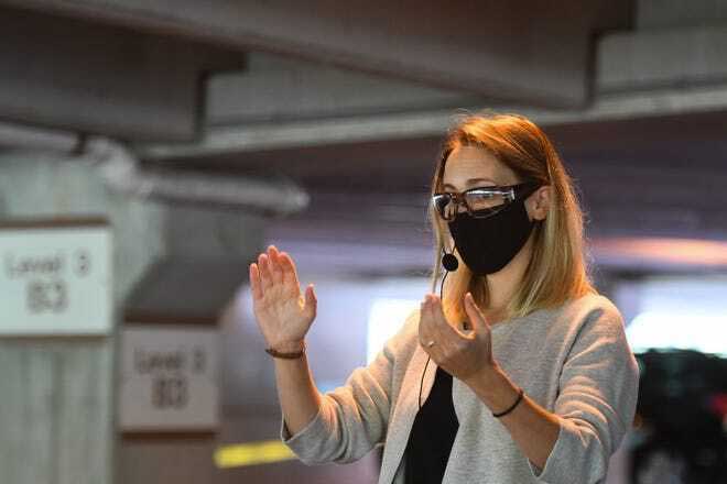 Donned in a mask and safety glasses, Jennifer Heder, a first year doctoral student in choral conducting leads a rehearsal in the Kellogg Center parking garage. Photo by Mathew Dae Smith/Lansing State Journal.