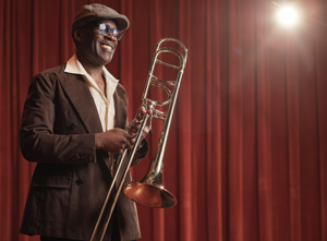 Photo of Kenneth Thompkins smiling with his trombone.