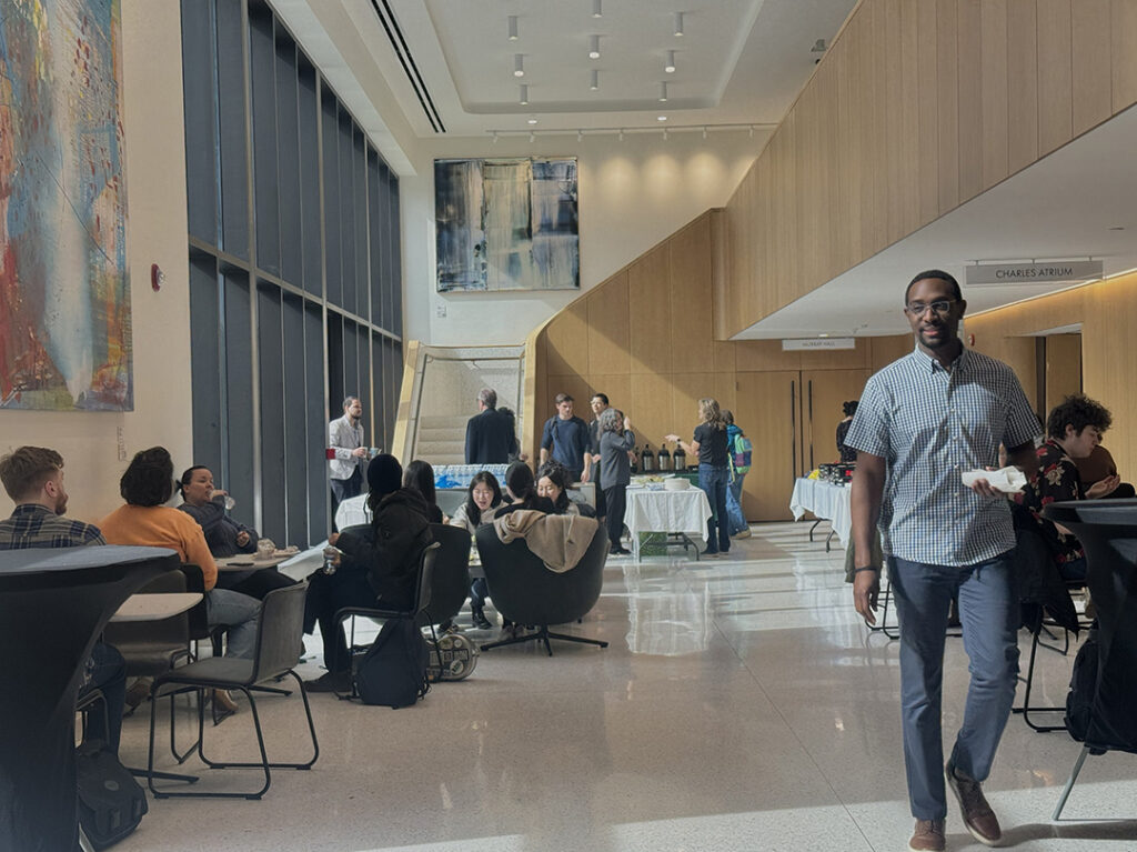 long view of high ceilinged atrium, students on both sides, man walking on rigth toward camera