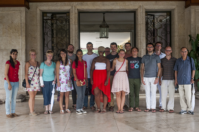 a group of students and faculty stand in front of an open doorway in Cuba