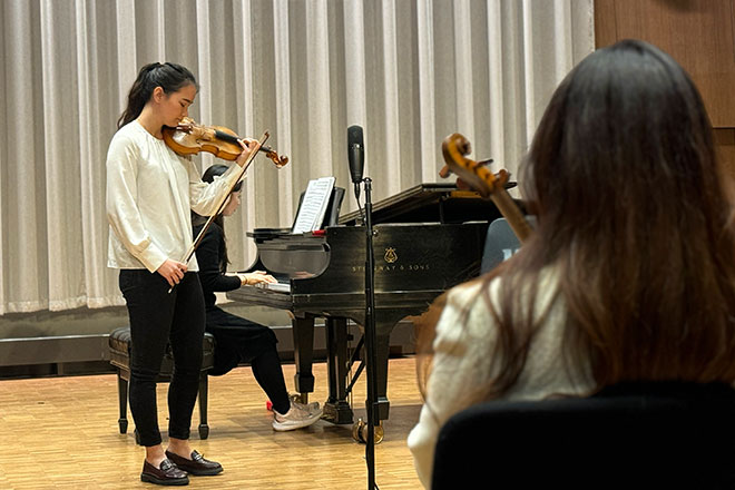 Student takes direction from a guest violinist during a masterclass