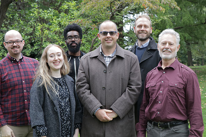 Group of Theory faculty standing and posing for he camera with smiles