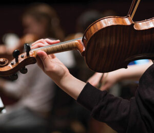 Close up of student during a rehearsal playing the violin