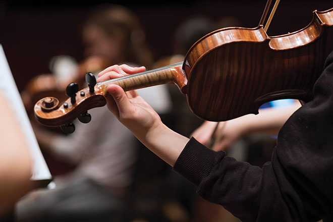 Close up of student during a rehearsal playing the violin