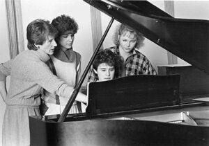 Black and white photo of Barbara Dixon and others on piano