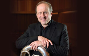 Phil Sinder headshot, posing with Tuba