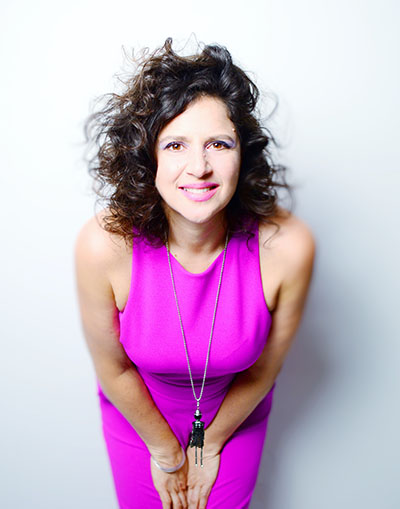 woman in pink dress smiles and leans toward the camera