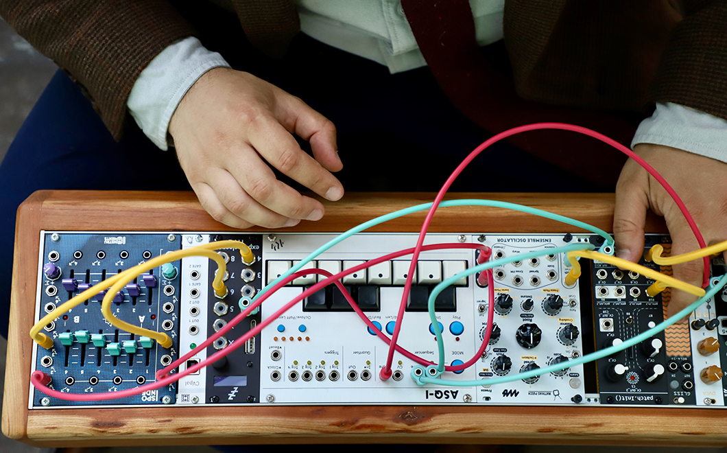 man's hands seen operating an electronic device with several knobs, buttons, and colorful wires