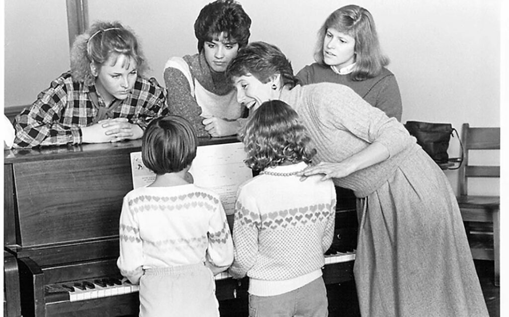 Black and white photo of Barbara Dixon teaching piano