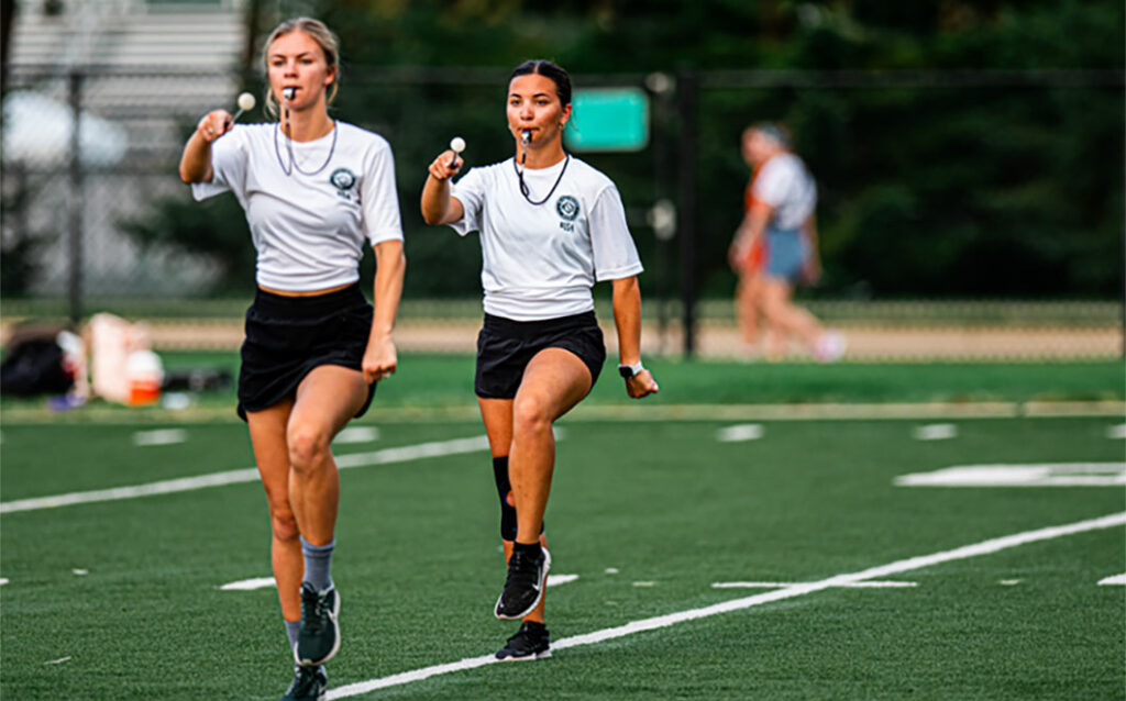 Two girls marching in line at the Spartan Marching Band practice field 