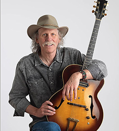 man in cowboy hat holds guitar