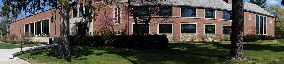 Panoramic view of the Music Building and Billman Music Pavilion addition. Trees in foreground, daytime with greenery and summer setting