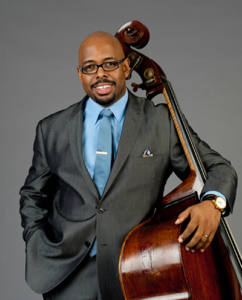 man in suit smiles and poses with his upright bass