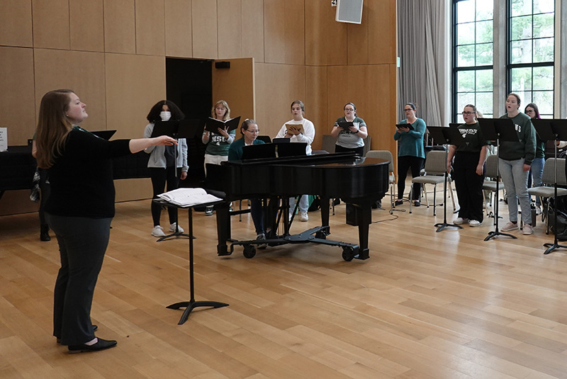 student conductor with choir in rehearsal room