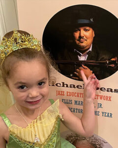 Michael Dease's daughter smiling infant of a poster of him 