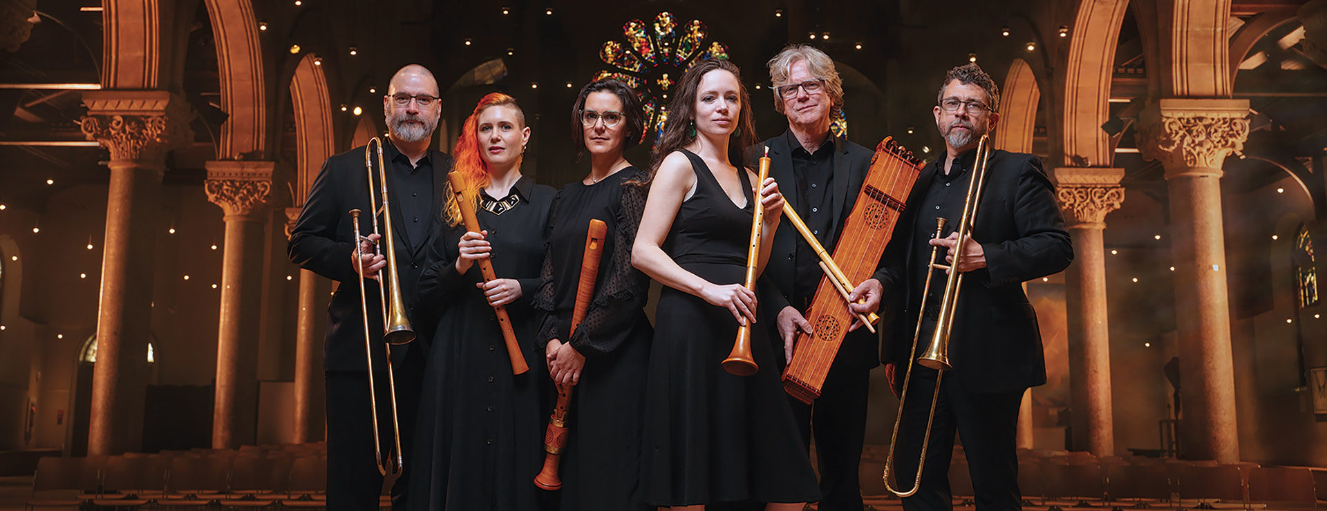 “All excellent and esteemed,” Piffaro, The Renaissance Band 6 musicians posed standing with their instruments.