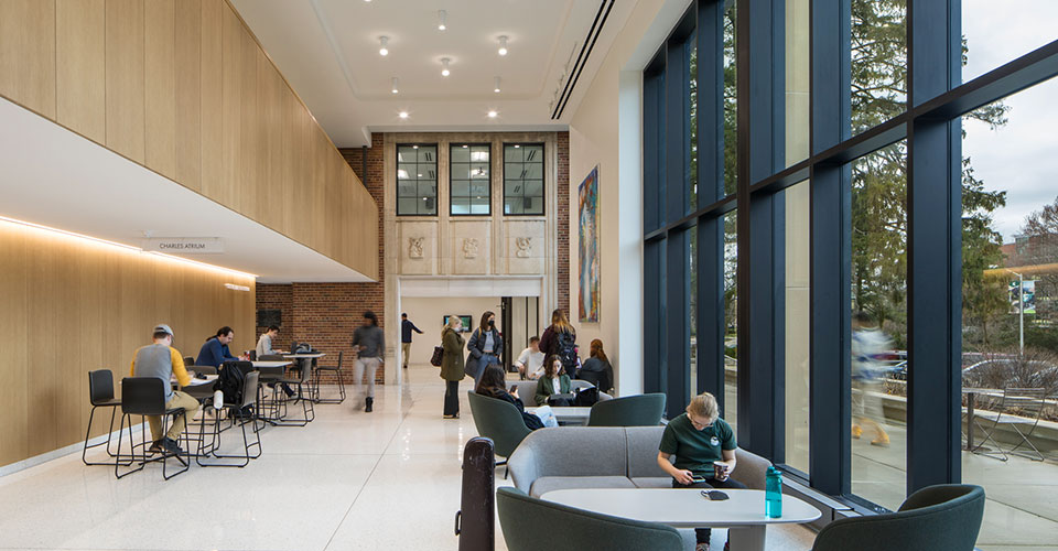 Atrium of the Billman Music Pavilion, natural light in the space with a variety of student seated in the space, abstract paintings on the walls