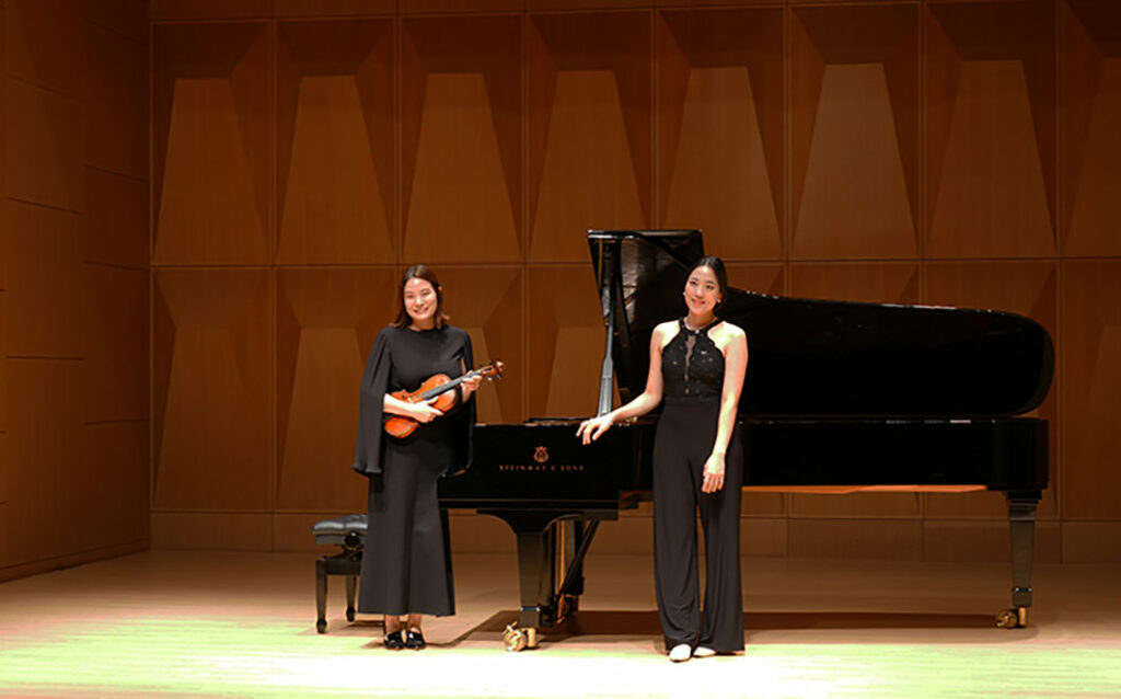 Two alumni smiling on stage 