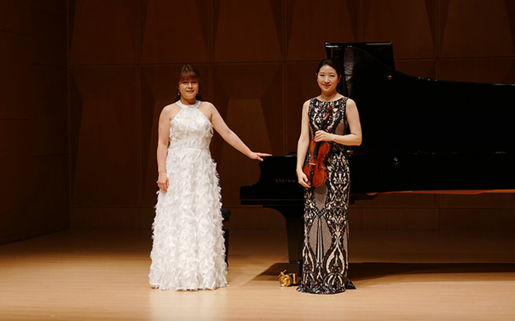 Two women smiling on stage 