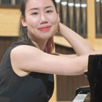 photo portrait, Jingting Huang looking at camera and smiling, organ instrument pipes in the background