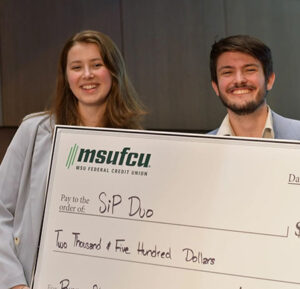 Duo holding up a large check from MSUFCU