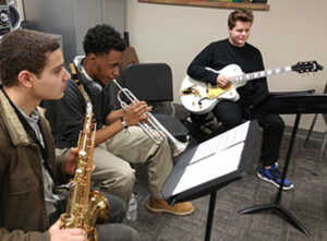 Students in a classroom playing a variety of instruments 