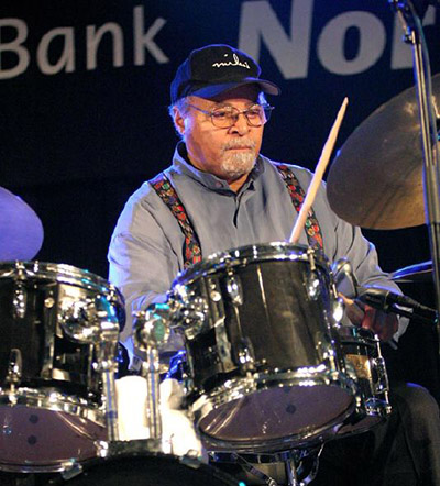 man wearing baseball cap and playing drums