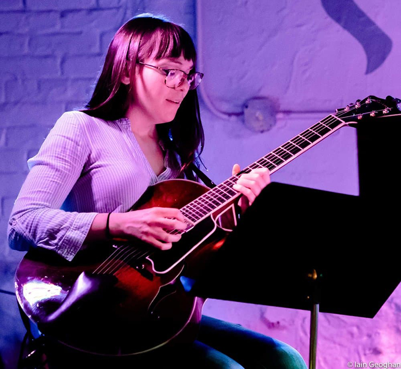 woman plays guitar on stage