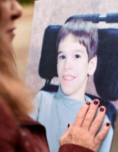 Photo of a young boy with woman's hand touching the frame 