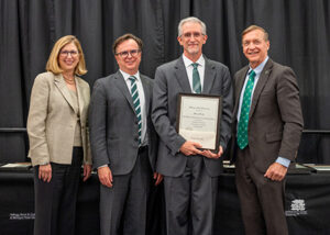 Michael Kroth smiling with award and MSU faculty