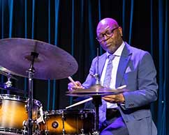 man playing yellow drum set, eyes closed