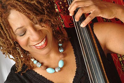 close up of woman looking down and smiling as she plays the upright bass