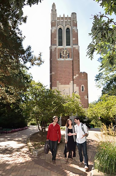 Three students walk and talk in front of Beaumont Tower on the campus of Michigan State University.