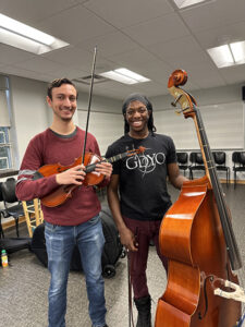 Two music students smiling with their instruments 