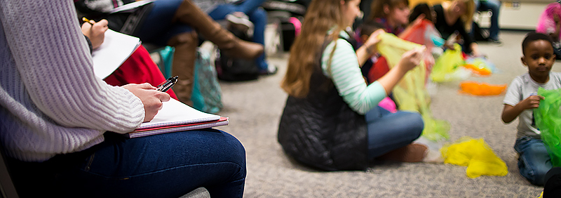 parents and children in class sitting on floor and playing with ribbons