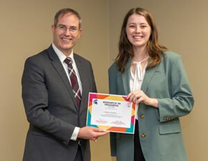 Student and faculty member smiling and holding a certificate 