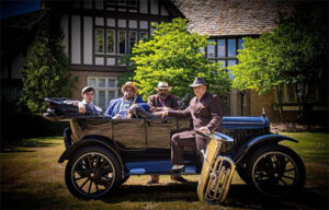 Men posing by an old car with their tubas 