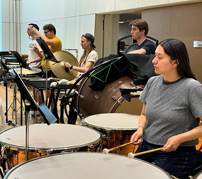 a row of five percussionists playing during a rehearsal