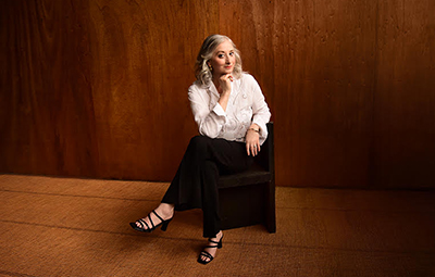 woman seated in an empty room with wood floors and walls