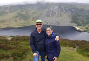 Lizbeth and Rick Sherman smiling in front of mountains in Ireland 