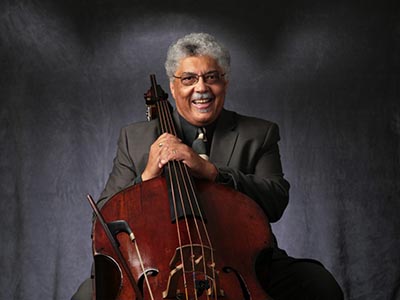 man smiles and poses with an upright bass