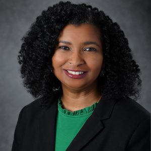 person in dark blazer with green shirt