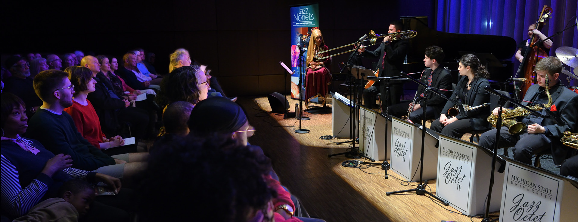 Jazz nonets showing audience and jazz players watching as trombone player solos.