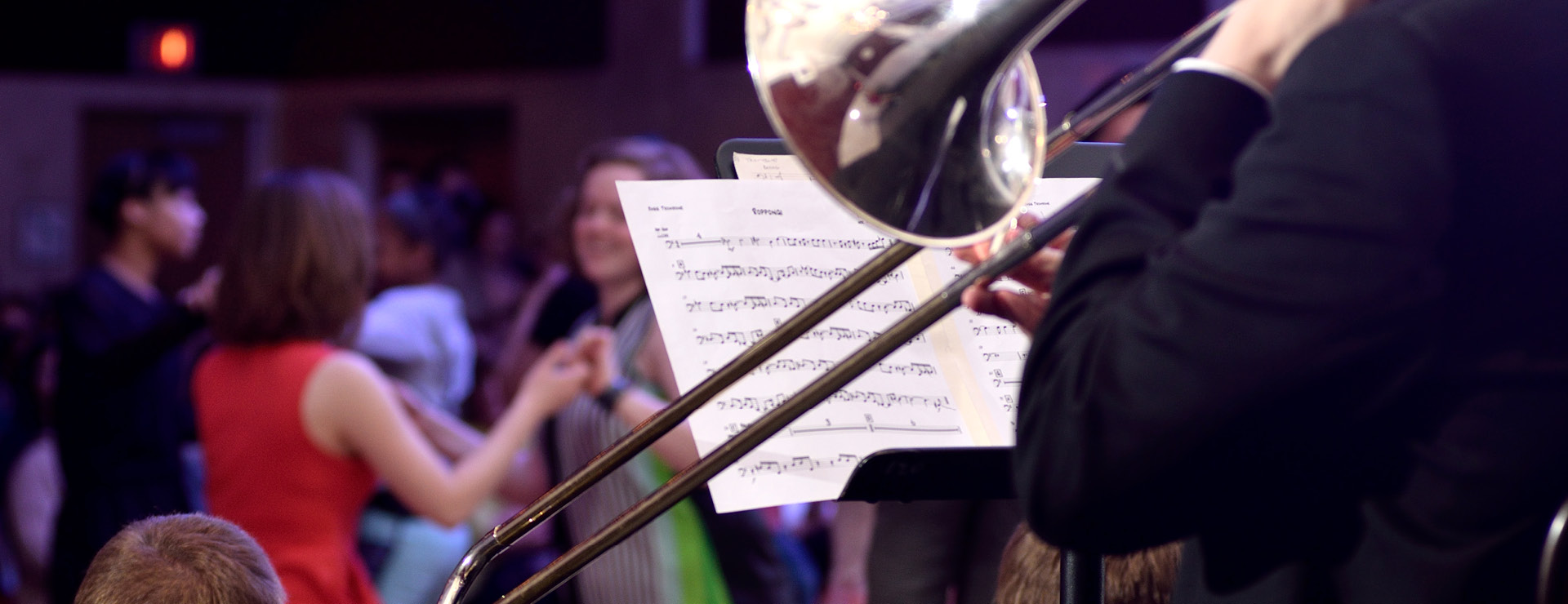 Jazz swing dance showing trombone player in foreground and audience members dancing in the background