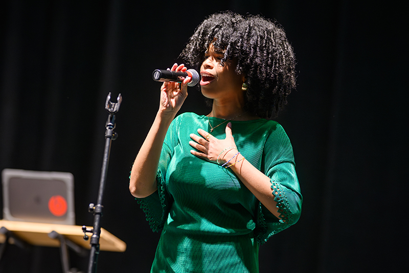 woman sings into microphone on stage