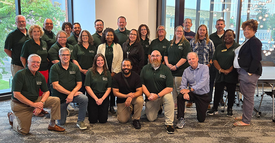 Large group photo of staff for the MSU College of Music. Stacked in three rows with the front row kneeling and the the tallest people in the back