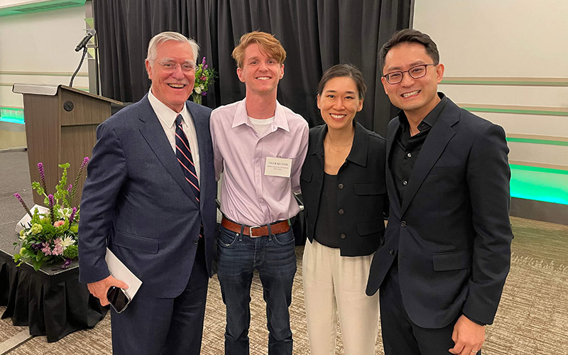 four faculty members stand arm in arm, smiling