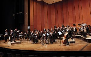Members of the MSU Wind Symphony performing on the Cobb Great Hall Stage of Wharton Center. Instrumentalists intently playing while be directed by conductor Kevin Sedatole.